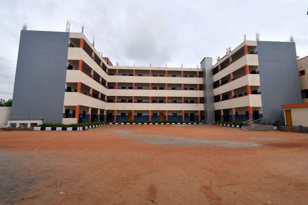 School front building exterior with transport vans and staff members